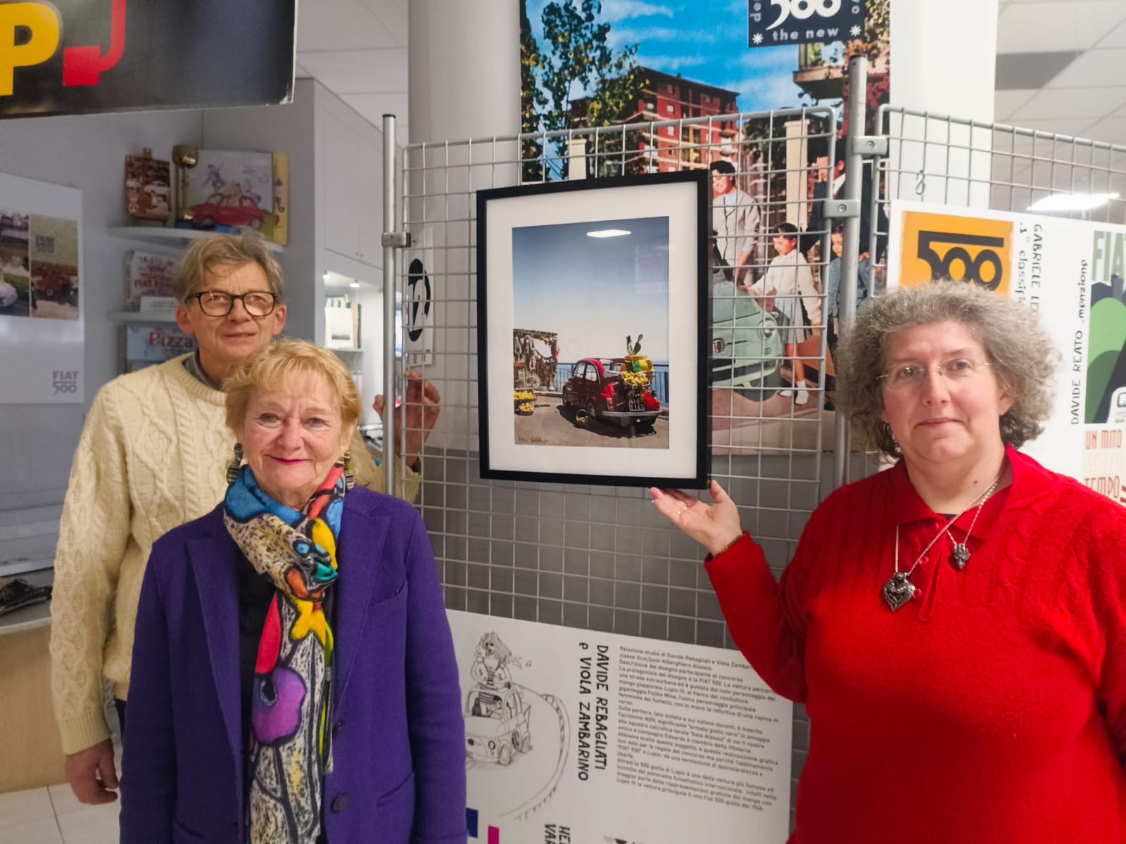Fiat museum officials with photo of Fiat hanging in gallery